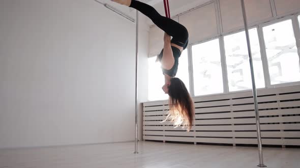 A Young Gymnastic Woman Performing Tricks on the Ring Hanging Under the Ceiling