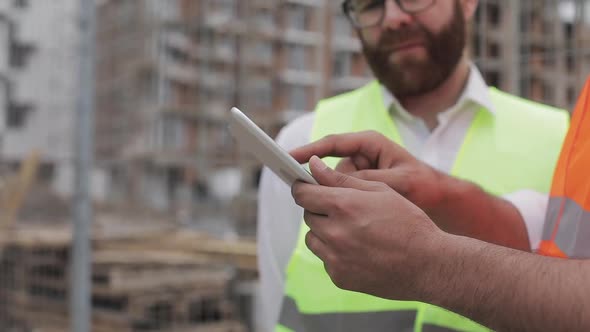 Close Up of Architect Hands Using Tablet Near Construction Site. The Builder and Architect