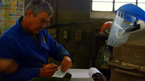 Male worker writing on clipboard in foundry workshop 4k