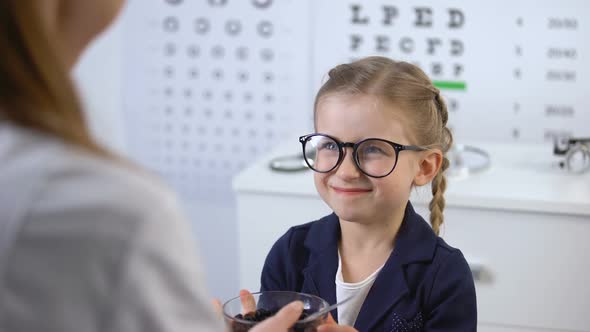 Happy Schoolgirl Eating Blueberries on Recommendation of Optician, Eye Vitamins