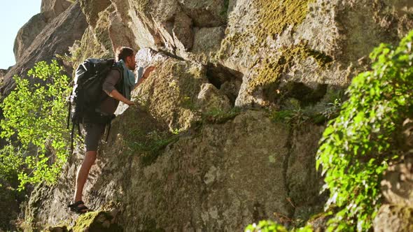 Bearded Caucasian Male in Shorts and Sandales Climbing Up Cliff in Slowmotion