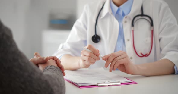 Close Up of Female Doctor Writing Prescription for Patient in Clinic Office