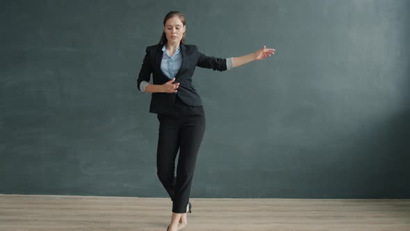 Slow Motion of Beautiful Young Woman in Suit Dancing Alone on Gray Background