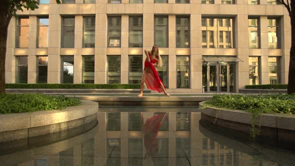 Beautiful Young Girl Dancing on the Street of a Modern City and Is Reflected in the Water