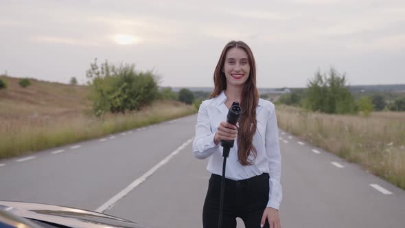 Girl Stands on the Road and Holds the Charger