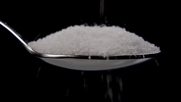 Sugar crystals pour into a spoonful of sugar 