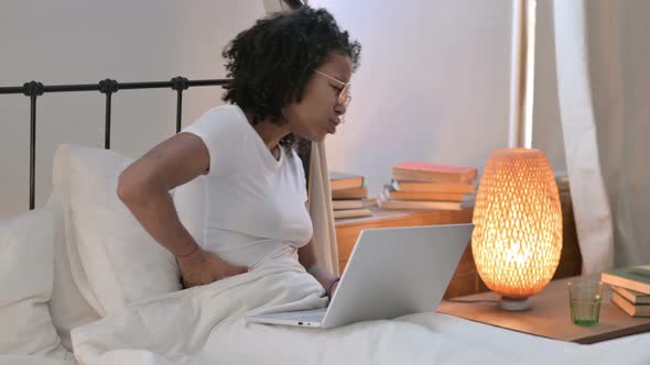 African Woman with Laptop Having Back Pain in Bed 