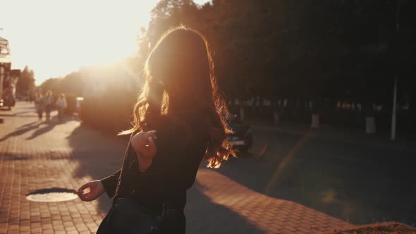 A Sophisticated Young Lady Puts on Sunglasses and Straightens Her Luxurious Hair While Standing on a