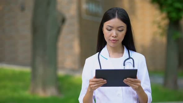 Female Nurse Checking Examination Results at Tablet PC