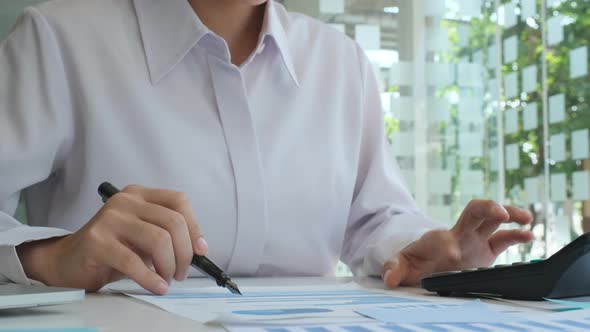 Businesswoman using calculator to calculate and analyse investment merketing data.