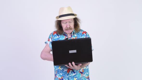 Happy Senior Tourist Man Smiling While Using Laptop