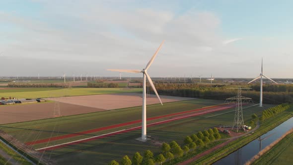 Scenic View Of Wind Turbines And Electricity Towers With Small River Stream In Flevoland, Netherland