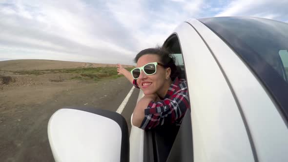 Beautiful woman out of car window enjoying the trip