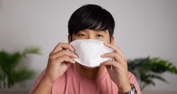 Man wearing face mask sits on couch in living room.