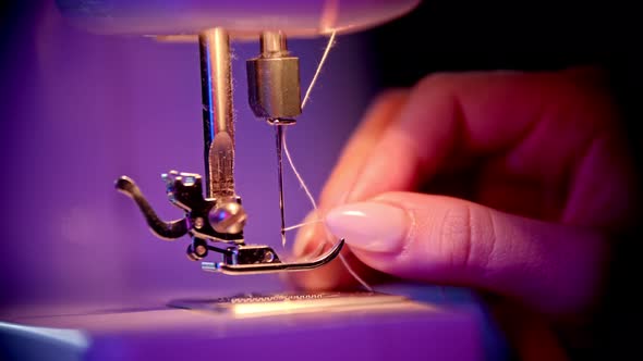 Hand of Seamstress Puts a Thread in the Eye of a Needle