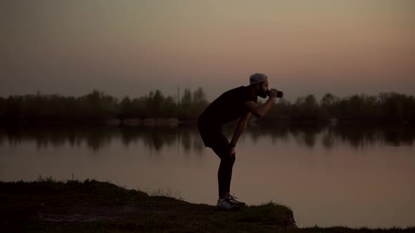 Tired Runner Drinking Water At Dusk. Triathlete Drinking Isotonic In Running Pause.Ironman Triathlon