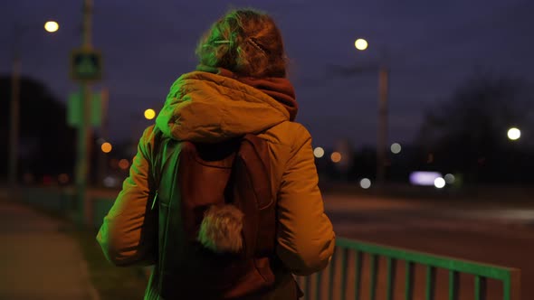 Back View of Woman Looking at the Night Road Traffic