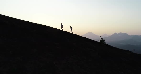 Runners running up a mountain at sunset