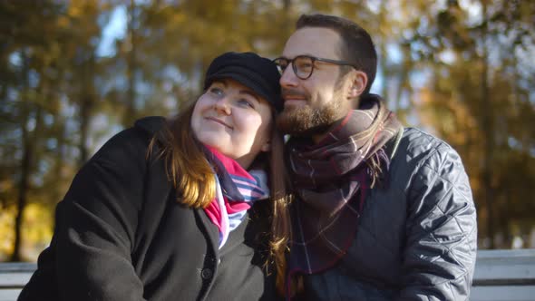 Young Happy Couple Having Date Embracing on Bench in Autumn Park