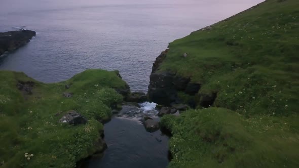 Small Waterfall Falls Into the Sea From the Cliffs