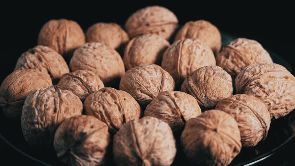 Lot of Walnuts in the Shell are Spinning on a Black Background