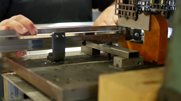 Worker making holes in metal plates with a punching drilling machine