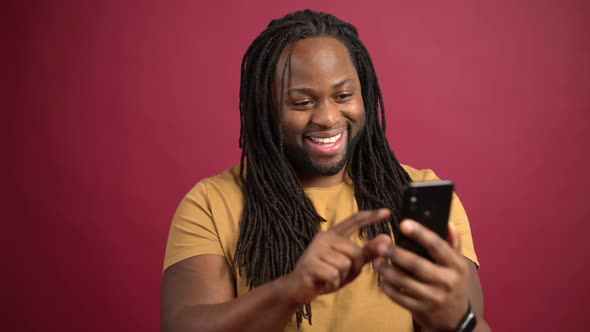 Cheerful AfricanAmerican Man with Dreadlocks Enjoys Spending Time Online