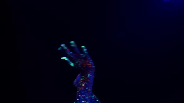 Hands Stained with Colored Fluorescent Paint Dancing on a Black Background