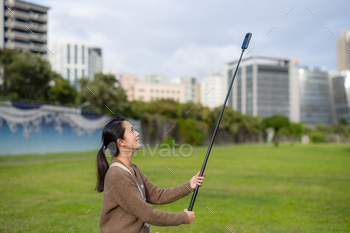 Woman use 360 degree camera to take video at park