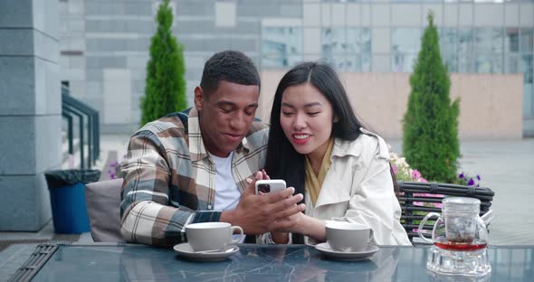 Two Charming People in Casual Cozy Clothes Sitting at the Table in a Summer Terrace of a Cafeteria