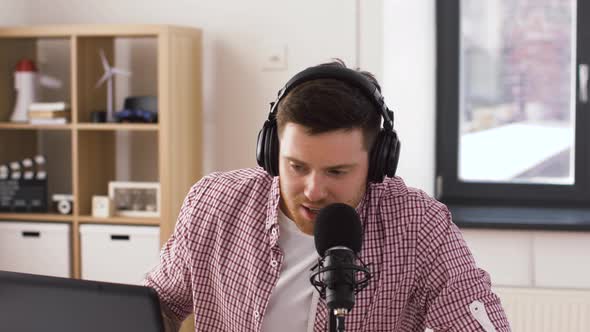 Man in Headphones with Laptop Speaks To Microphone 