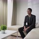Asian man make a video call, interview, or conference sitting on a sofa with white concept room - VideoHive Item for Sale