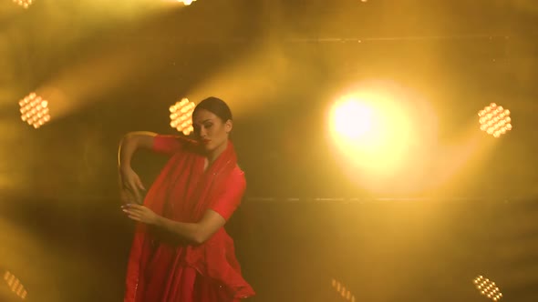 A Young Girl Dancer in a Red Sari. Indian Folk Dance. Shot in a Dark Studio with Smoke and Yellow