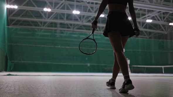 Sporty Woman is Walking on Tennis Court Indoors Throwing Ball and Catching Rear View Professional