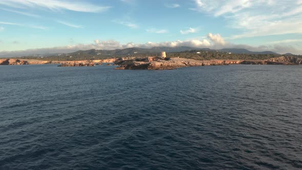 Ibiza pirate tower from a distance. Aerial view moving towards the tower showing the surroundings.