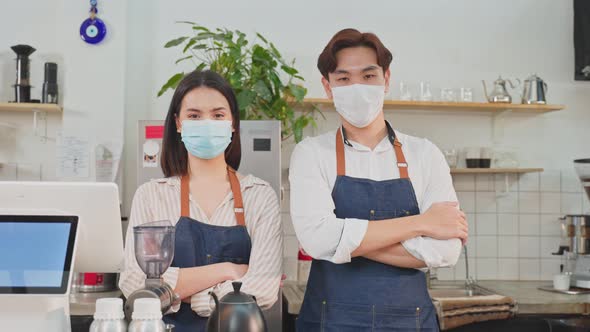 Portrait of attractive Asian barista waiter and waitress stand and crossing arm at restaurant cafe.