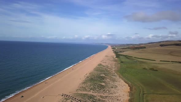 Aerial tracking from right to left with slight rotation looking up the vast length of Chesil Beach l