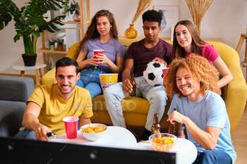 Group of friends watching a soccer game on television at home.