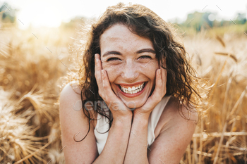 Happy beautiful woman smiling at camera in a wheat field - Delightful female enjoying summertime sun