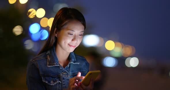 Woman use of smart phone in city at night