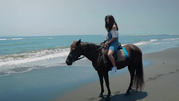 Cute Chinese Teenager Rides a Horse On The Beach In Bali