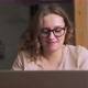 Woman with Glasses is Sitting at Laptop and Texting with Someone or Preparing Work Report - VideoHive Item for Sale