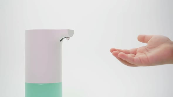 An Automatic Soap Dispenser Is Used By a Small Child on an Isolated Background. Close-up of a Small