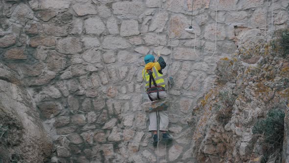Professional Climber at Work. Repair of the Facade of the Building. Painter Climber Working on House