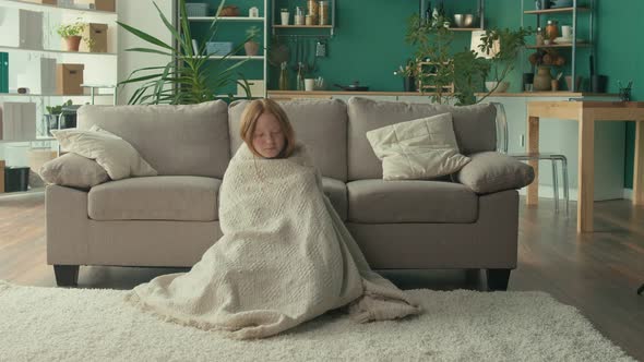 A Depressed Teenage Girl Covers Herself with a Blanket in Her Living Room