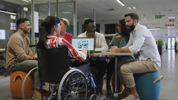 Happy diverse male and female business colleagues and disabled businesswoman talking in office