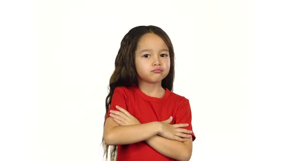 Portrait of Little Girl Shows Emotion, Crosses Hands Posing at White Background