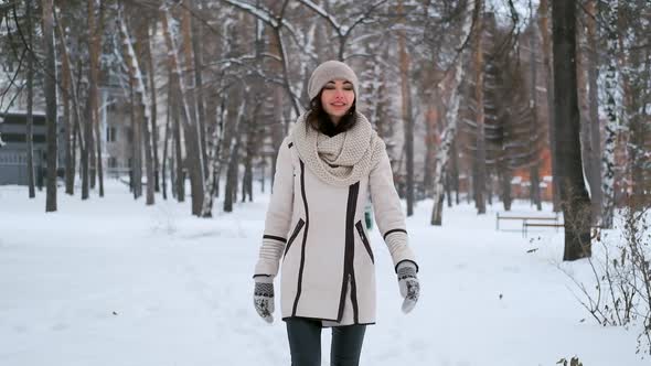 Beautiful Young Woman Is Walking in the Park in Winter and Smiling