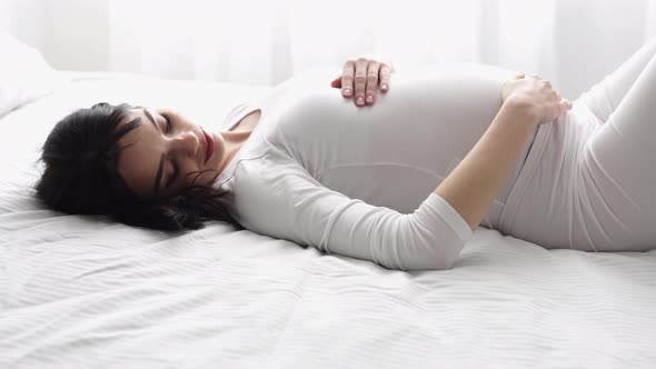 Pregnancy. Beautiful Woman Lying On Bed And Touching Baby Belly