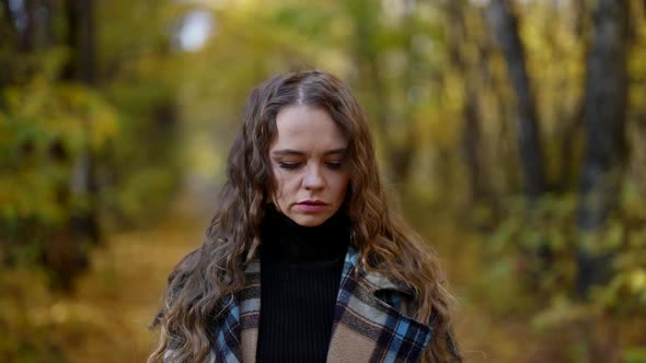 Lonely Sorrowful Woman is Walking in Park Alley in Autumn Day Under Falling Leaves